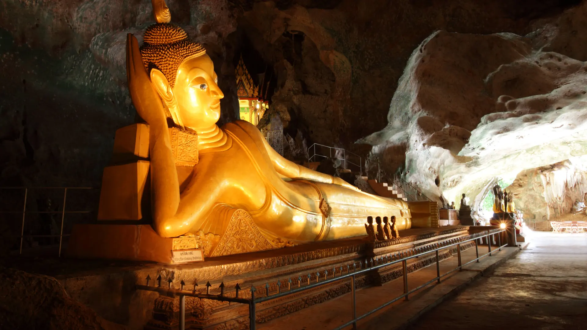 A golden reclining Buddha lit up in the Wat Suwan Khuha cave, Phang Nga, Thailand